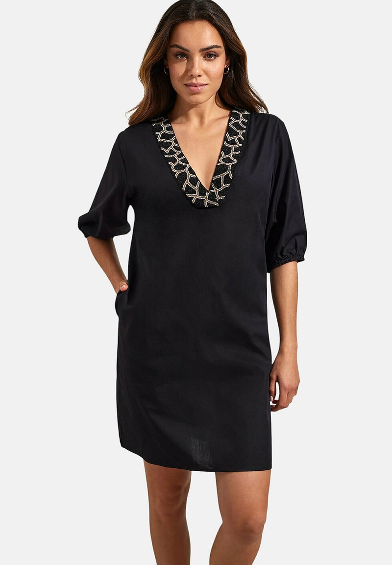 Zwarte jurk met een V-hals en 3/4 pofmouwen, met een geometrisch bewerkt ontwerp langs de halslijn. Gladde textuur en details van zakken.