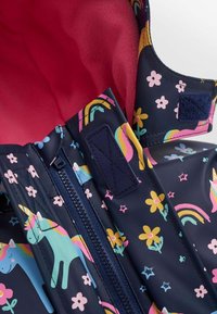 Marine regnjakke med mønstre af enhorn og blomster, lyserød fleece-foring, blå lynlås og velcro-lukninger. Holdbart, vandtæt materiale.
