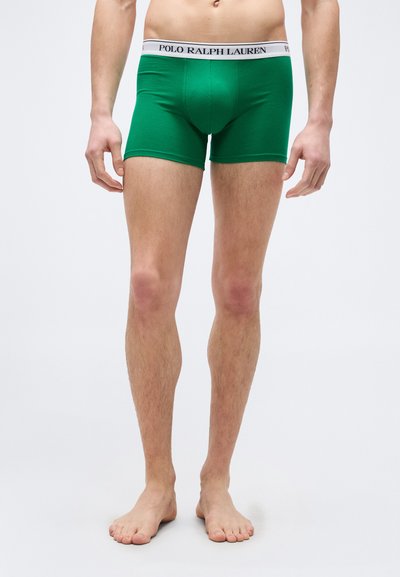 Άνδρας μοντέλο που φοράει πράσινα εσώρουχα boxer από την Polo Ralph Lauren, στέκεται ξυπόλυτος μπροστά σε απλό λευκό φόντο.