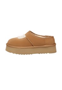 Tan slip-on shoe with a textured upper and fluffy accent, featuring a thick, ridged midsole and rounded toe for comfort.
