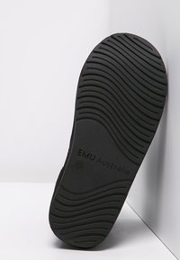 Czarna gumowa podeszwa z teksturowanym falistym wzorem, oznaczona "EMU Australia". Płaski design, odpowiedni do obuwia, pokazujący trwałość.