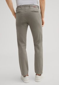 Pantaloni grigi realizzati in tessuto testurizzato, con una linea dritta, due tasche posteriori con zip e un orlo leggermente accorciato.