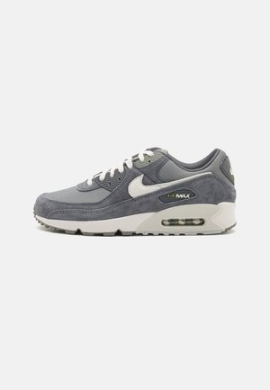 Szary i biały sneaker Nike Air Max z materiałów zamszowych i siateczkowych, widoczna poduszka powietrzna w podeszwie oraz białe sznurówki na jasnym tle.