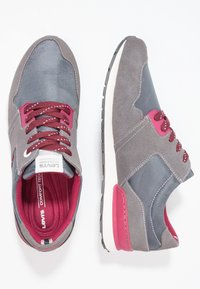 Graue Sneakers aus einer Mischung aus Wildleder und Textilmaterialien. Enthält burgunderfarbene Akzente und Schnürsenkel, eine weiße Zwischensohle und eine strukturierte Außensohle.