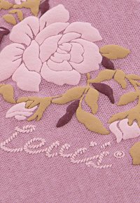 Rosas rosas delicadas y hojas están bordadas en una tela de lavanda texturizada, con el nombre de la marca "Levi's" en un estilo cursivo.