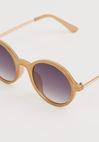 Ochelari de soare rotunzi cu o ramă bej translucidă, lentile violet cu gradient și brațe din metal cu ton de aur. Textură netedă, detalii hardware minime.