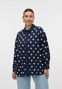 Chemise boutonnée bleu marine à pois blancs, avec un col, des manches longues et une coupe décontractée. Tissu texturé.