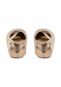 Pereche de balerini metalizați aurii-roz cu curele elastice, văzuți din spate pe un fundal alb.