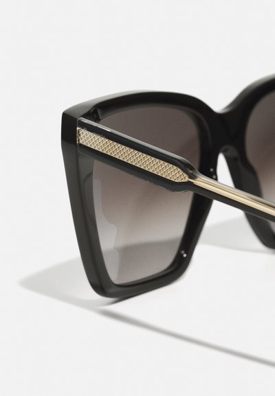 Black plastic sunglasses with a geometric design, gradient dark lenses, gold-accented temples featuring a textured pattern.