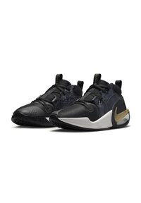 Scarpe da ginnastica nere con una tomaia texturizzata, accenti lucidi, suola bianca e un logo Nike dorato sul tallone. Design elegante con linee moderne.