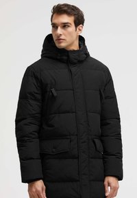 Schwarze Steppjacke mit Kapuze, durchgängigen Brusttaschen mit Reißverschluss und einer geknöpften Klapptasche, mit einem gesteppten Muster und geradem Schnitt.