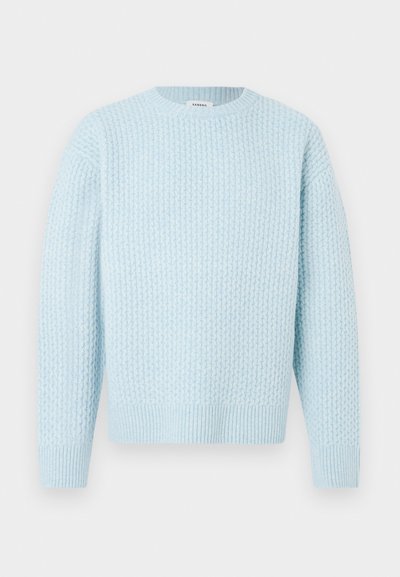 Svetlo modra teksturirana pulover s krožnim ovratnikom, dolgimi rokavi in ribastimi manšetami ter robom. Ima edinstven pleteni vzorec.