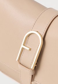 Beige bőr kézitáska texturált felülettel, aranyszínű fém csattal és részletes varrással az éleken.