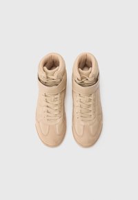 Baskets montantes en cuir et daim beige avec un col rembourré, une fermeture à lacets et des détails de couture minimalistes. Semelle en caoutchouc.