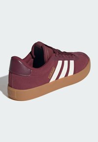 Burgundské semišové tenisky s bílými pruhovanými akcenty, vybavené gumovou podrážkou a polstrovaným límcem pro pohodlí a podporu.