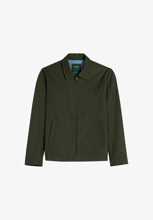 Ciemnozielona kurtka na zamek z ostrym kołnierzem, dwoma bocznymi kieszeniami i subtelnym logo na piersi, pokazana na płasko na białym tle.