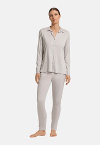 Lichtgrijze pyjama set bestaande uit een knoopsluiting met lange mouwen en een aangesloten broek, beide gemaakt van zachte, rekbare stof met een gladde textuur.