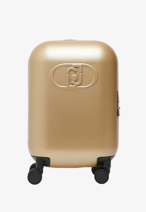 Kompaktowa walizka o twardej, złotej powłoce z czterema czarnymi obrotowymi kółkami oraz wytłoczonym geometrycznym logo z przodu.