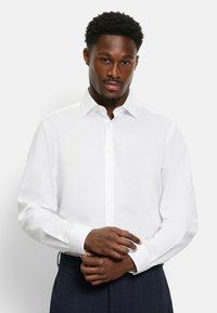 Weißes Langarmshirt aus glattem Stoff mit klassischem Kragen und Knopfverschluss. Mit Knopfmanschetten und taillierter Passform.
