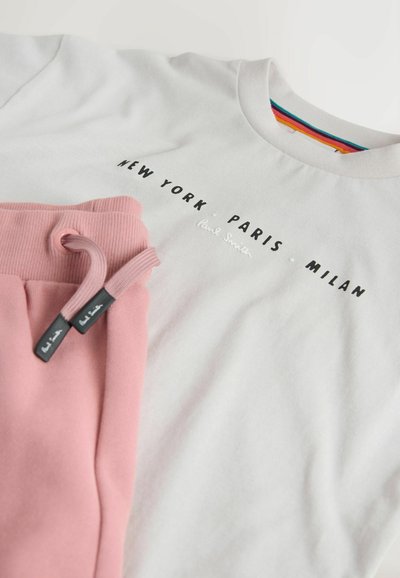 Hvid sweatshirt med teksten "New York Paris Milan" og lyserøde træningsbukser med snore, begge med Paul Smiths brandingdetaljer.