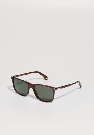 Óculos de sol com padrão tartaruga, lentes verde-escuro e formato retangular. Apresenta a marca Polaroid nas hastes.