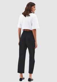 Wit crop T-shirt gecombineerd met zwarte skinny jeans, met een gladde textuur en een recht ontwerp. Zwarte instappers zichtbaar.