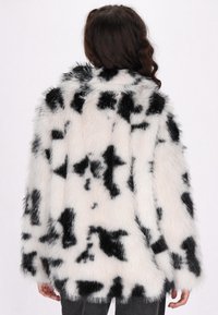 Black and white faux fur coat with a cow print pattern, featuring a soft texture, wide sleeves, and a relaxed fit, shown from the back.