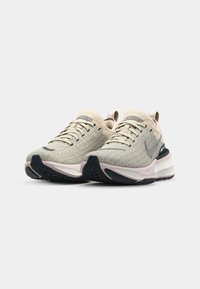 Beige Laufschuhe mit strukturiertem Obermaterial, Schnürverschluss und gepolstertem Schaft. Verfügt über eine rosa Zwischensohle und eine schwarze Gummisohle.