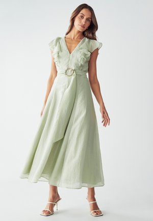 Robe longue de couleur vert clair avec des manches volantées et un décolleté en V, cintrée à la taille par un accent en anneau doré. Elle tombe jusqu'au sol, fabriquée en un tissu texturé.