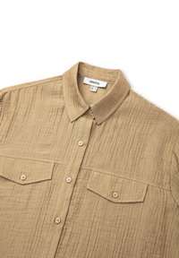 Beige Hemd aus strukturiertem Stoff mit Klapptaschen, einem spitzen Kragen und Kunststoffknöpfen. Hat eine lockere Passform und dezente Nähte.