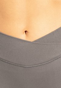 Grå leggings med høj talje har en ribbet tekstur og en V-formet taljelinje. Glat stof med elastisk stræk, velegnet til aktiv brug.