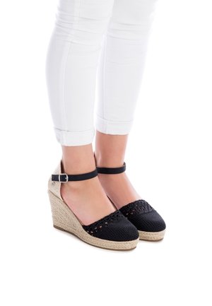 Sandalias de cuña trenzadas negras con suela de yute, que presentan una correa de tobillo negra y un diseño de punto intrincado en la zona de los dedos.