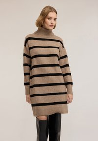 Abito maglione beige con strisce orizzontali nere, collo alto e maniche lunghe. Tessuto morbido e polsini a coste, che termina sopra le cosce.