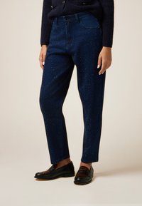 Jeans blu scuri con una vestibilità rilassata, caratterizzati da un motivo a pois di strass, design a cinque tasche e chiusura con bottone in vita.