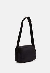 Borsa a tracolla nera con design morbido e imbottito, forma rettangolare e tracolla regolabile, dotata di una cerniera superiore per una chiusura sicura.