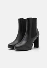 Botas de tornozelo em couro preto com acabamento liso, bico quadrado e salto bloco. Apresenta painéis elásticos laterais para fácil calçar e uma sola resistente.