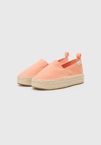 Espadrilles corail avec tige en toile, semelle intermédiaire en corde de jute et semelle extérieure en caoutchouc. Présente des goussets élastiques sur les côtés et une languette arrière.
