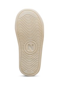 Suela de una zapatilla, de goma beige con un patrón en forma de ola, que presenta un logo circular con una "N" y el número "21" cerca del dedo del pie.