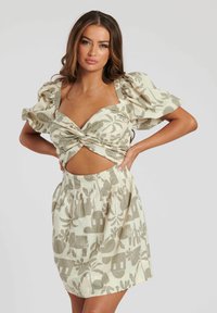 Conjunto ligero de dos piezas con un estampado floral que presenta una blusa con nudos en el frente y mangas abullonadas, junto con una falda de cintura alta en colores suaves y apagados.