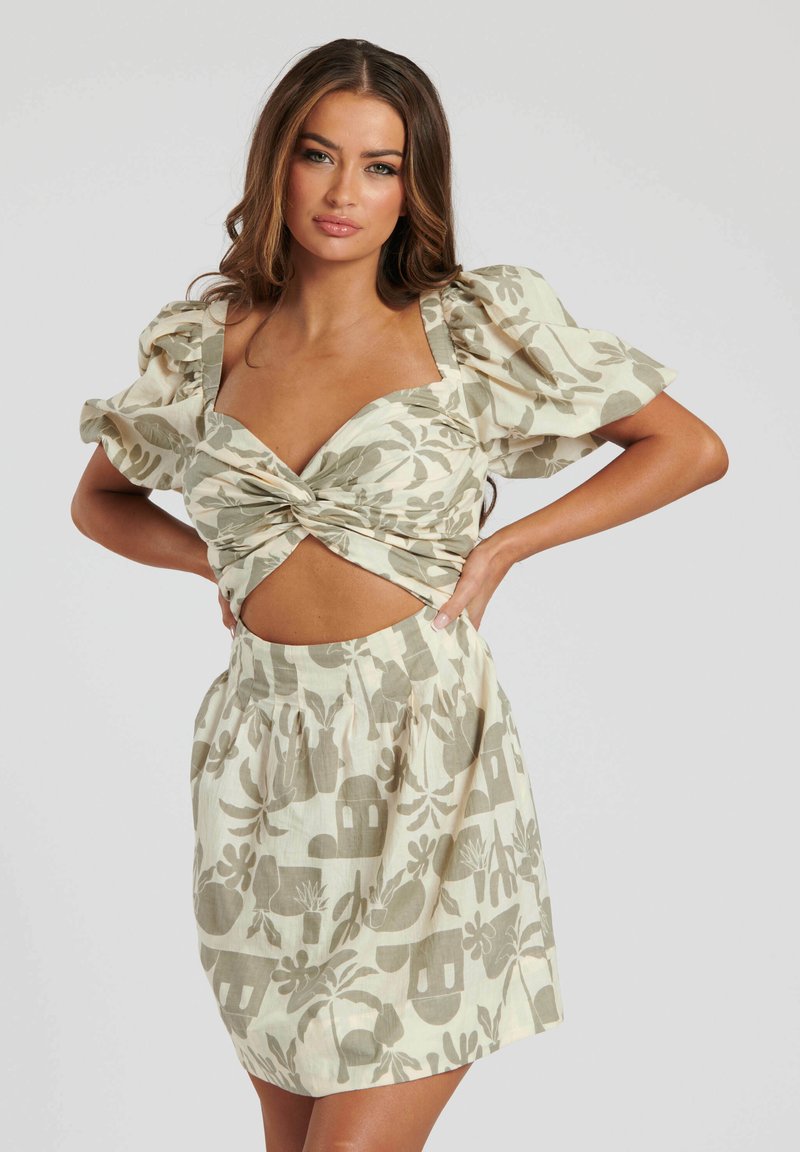 Conjunto ligero de dos piezas con un estampado floral que presenta una blusa con nudos en el frente y mangas abullonadas, junto con una falda de cintura alta en colores suaves y apagados.