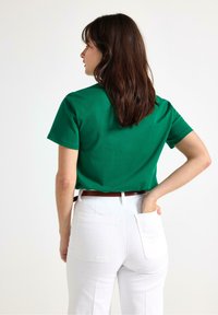 Grøn bomulds t-shirt med korte ærmer, afslappet pasform. Sammen med højhvide denim jeans i hvidt med baglommer og et brunt bælte.