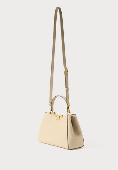 Beige Lederhandtasche mit strukturiertem Design, ausgestattet mit einem oberen Tragegriff und einem langen, verstellbaren Schulterriemen. Goldene Beschläge und Logo-Akzent.