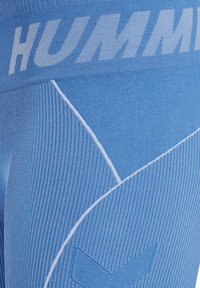 Blå träningsleggings med ribbat mönster, med vit logotyp vid midjan och geometriska mönster längs sidorna.