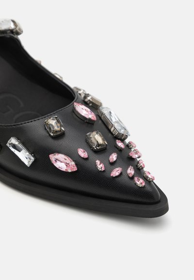 Black pointed flat shoe featuring various rhinestones in pink, clear, and gray, set against a textured leather surface.