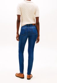 Smala blå denimjeans med en slät yta, med medelhög midja och bakfickor, kombinerat med ljusbruna loafers.