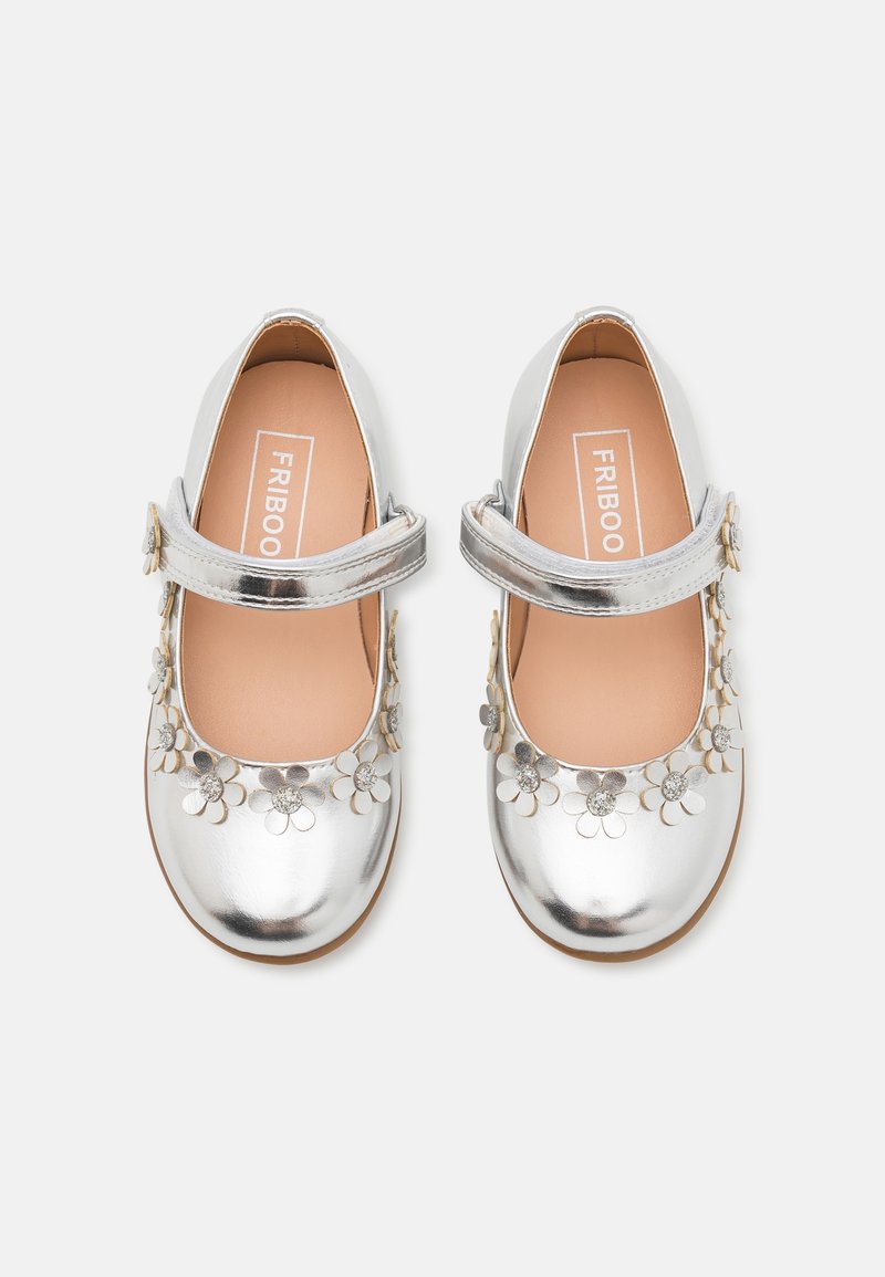 Stříbrné baleríny Mary Jane s lesklým povrchem, zdobené metalickými květinovými detaily a pásem se sponou. Hladký povrch, kulatá špička.
