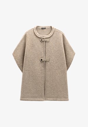 Beżowy wełniany poncz z okrągłym dekoltem, z przodu z zapięciami na guziki oraz szerokimi rękawami. Miękka tekstura i czyste detale ściegów w całym wyrobie.