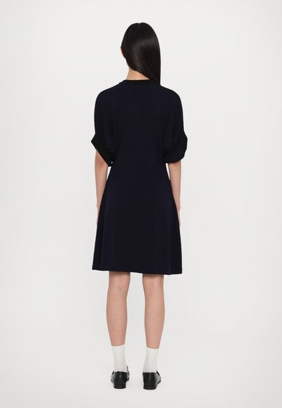 Robe bleu marine à manches courtes avec une coupe décontractée, dotée de manches retroussées et d'une jupe évasée, fabriquée en tissu doux.