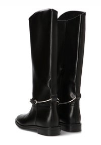 Botas de cuero negro hasta la rodilla con un diseño elegante, textura lisa y una correa con detalles en plata alrededor del tobillo. Suela plana, silueta sencilla.