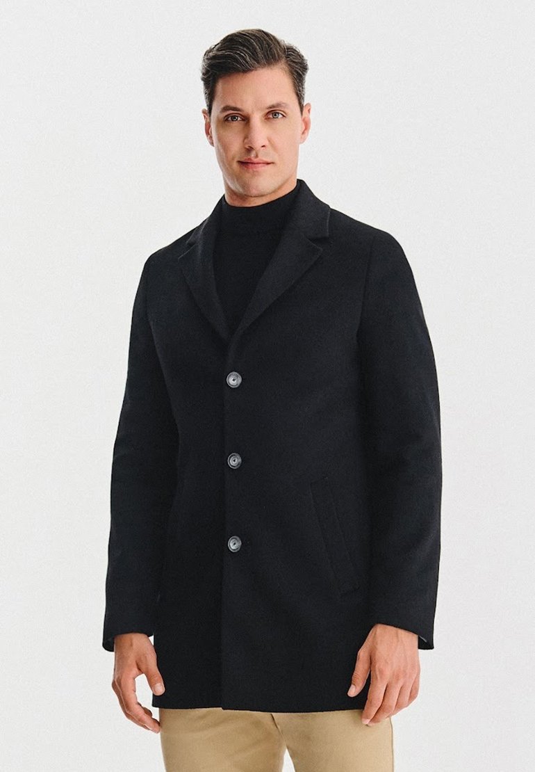 Czarny wełniany płaszcz z wyłogiem z nacięciem, trzema dużymi guzikami i bocznymi kieszeniami. Tkanina jest gładka, a krój dopasowany.